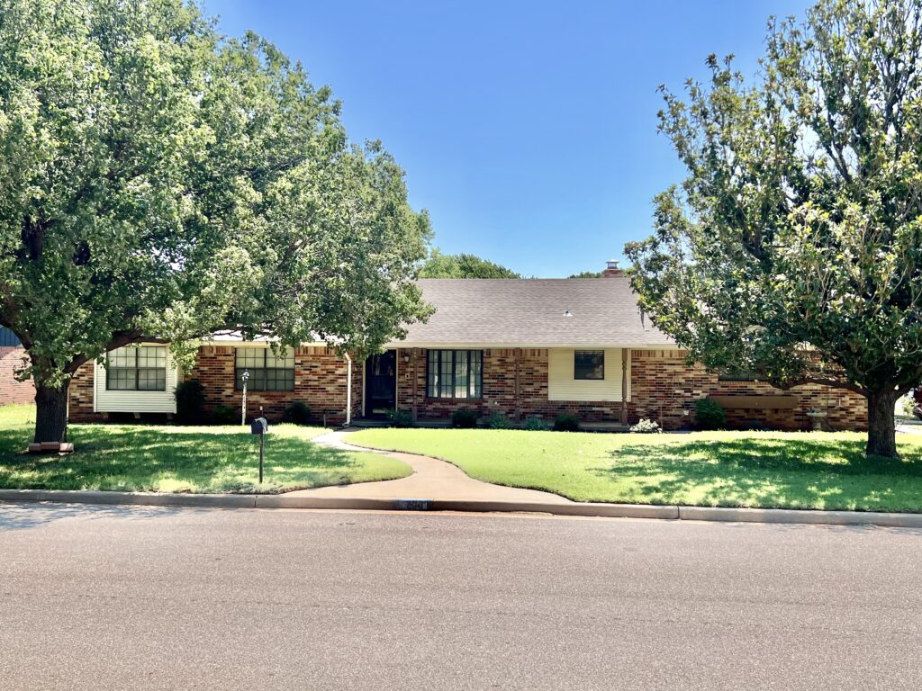 Brick home with spacious yard and trees.